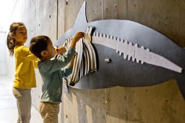 Two young museum visitors complete a puzzle of a harbor porpoise skeleton hanging on a wall.